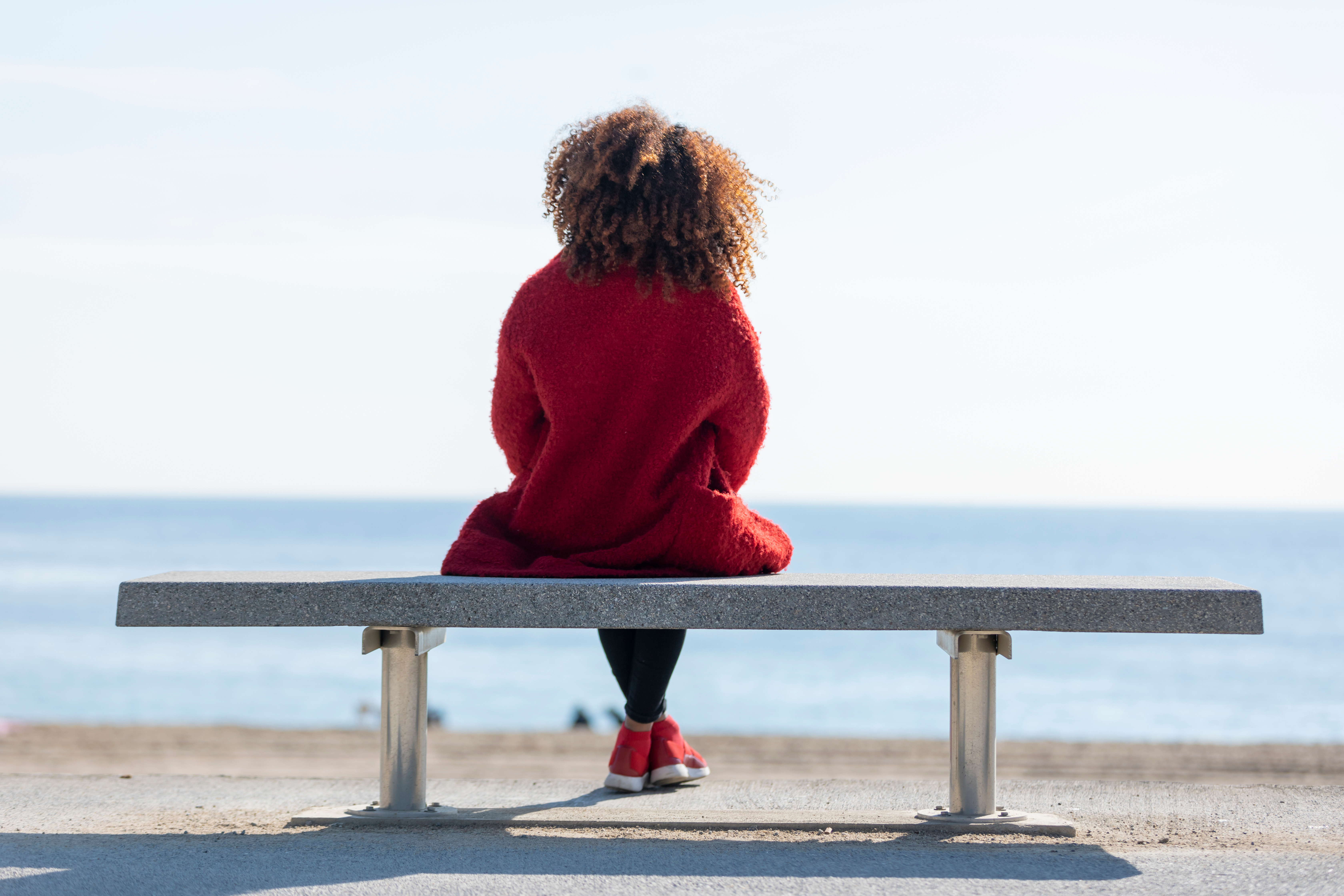 A person sitting on a bench struggling with symptoms of eczema. If you are also experiencing eczema symptoms, contact Vida-Flo today for IV hydration treatment.