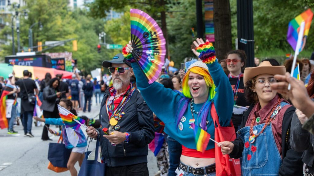 Atlanta Pride parade crowd waving rainbow fans and flags