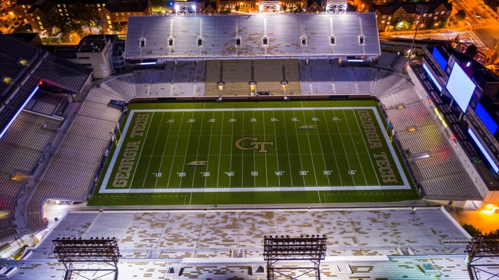 Aerial view of Bobby Dodd Stadium at Georgia Tech lit up at night with the campus around it