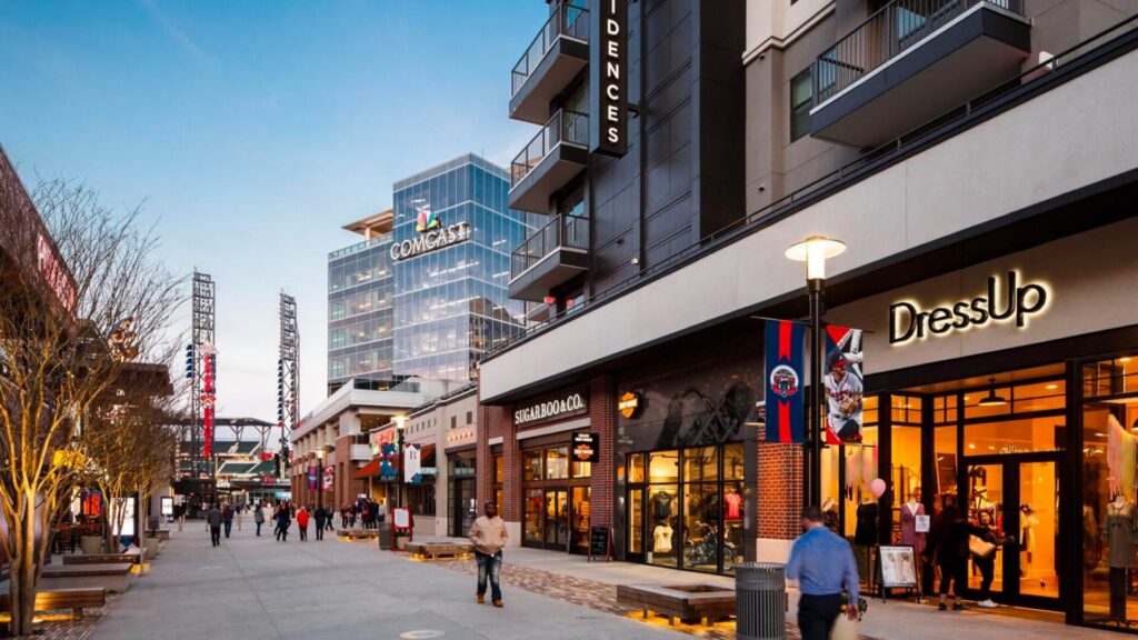 Shops along the walkway at The Battery Atlanta near Smyrna and Vinings, with the Truist Park light towers behind