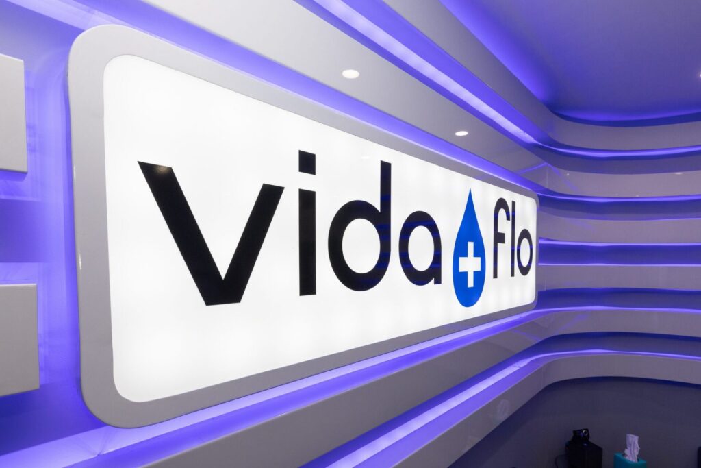 Illuminated Vida-Flo logo wall inside an IV hydration clinic